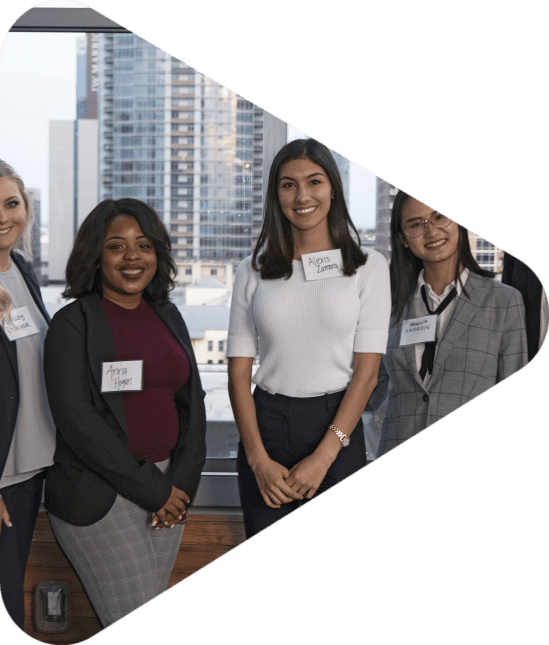 Five young women posing for photo at a UCREW event with buildings in background