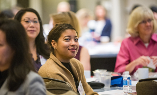 Woman smiling while listening to summit speaker