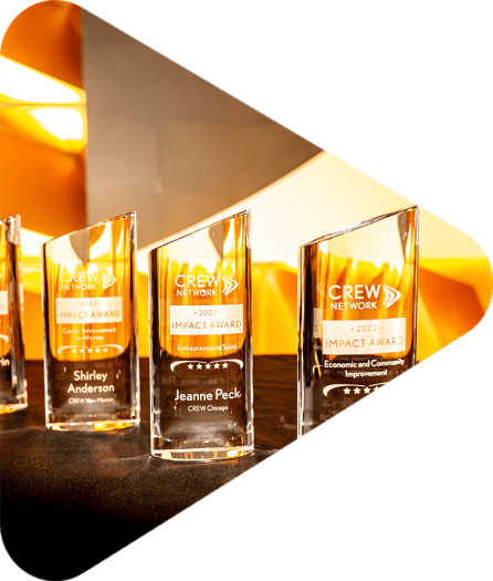 six glass CREW Impact Awards lined up on a table