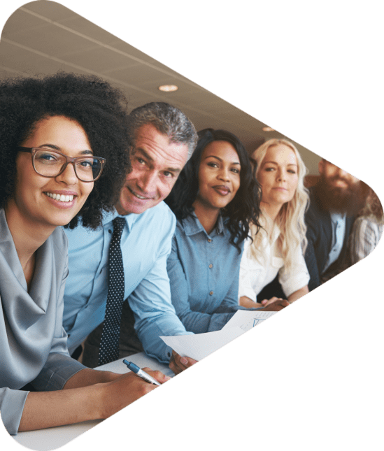 Portrait of a smiling group of diverse corporate colleagues standing in a row together at a table in a bright modern office