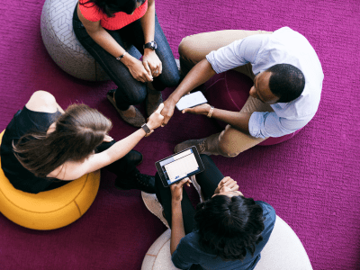 overhead shot of four people meeting and two of them shaking hands