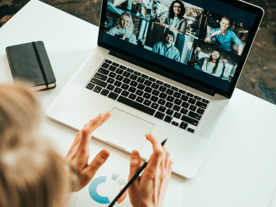 Woman has video call with her remote teammates using laptop.  White loft workspace